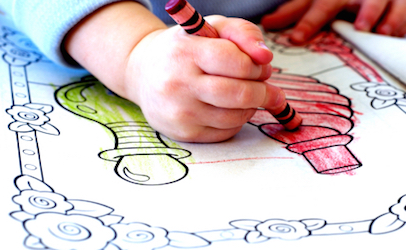 Little child coloring in coloring book with crayons