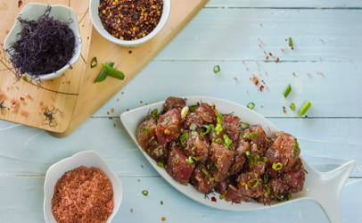 A traditional Hawaiian dish, ahi poke (in large dish) is garnished with a variety of spices and vegetables, including limu, or seaweed (upper left dish) which is sometimes purple in color.