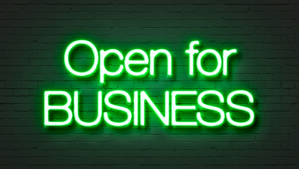 Open for business neon sign on brick wall background.