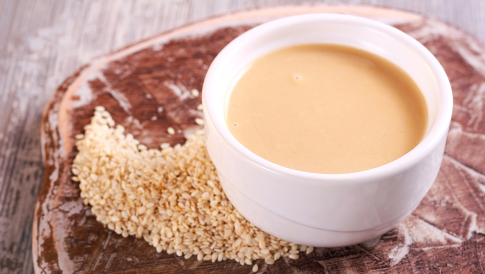 Tahini paste - sesame sauce on wooden board