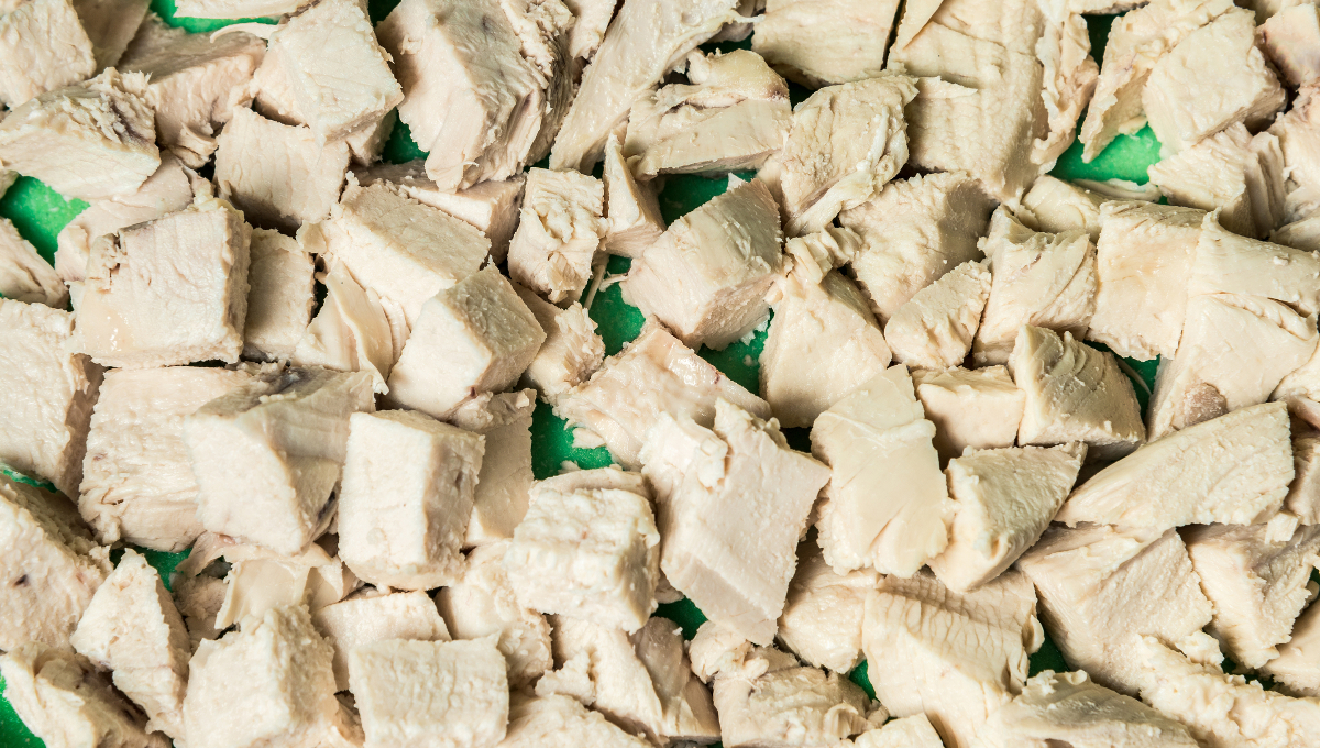 Diced boiled chicken meat on a green board. Horizontal frame