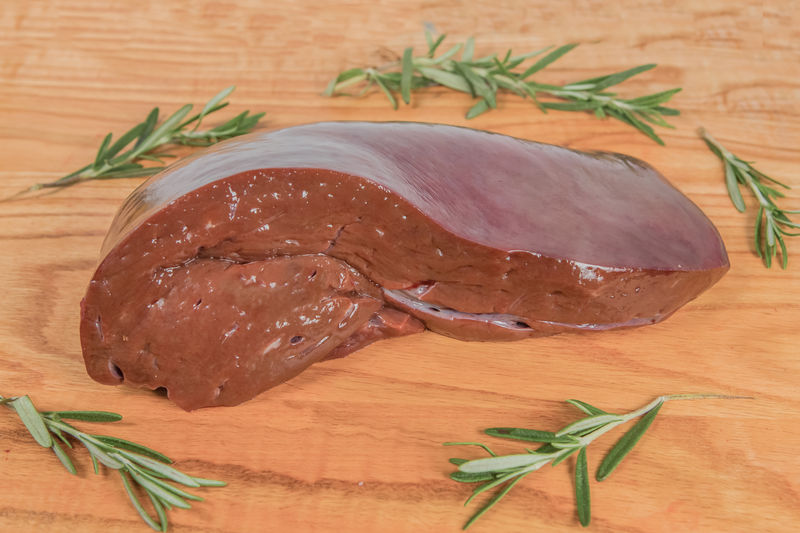 A fresh pig liver is cut on a wooden cutting board