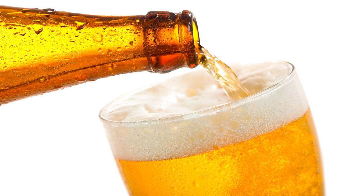 Sweating neck of a beer bottle being poured into a beer glass. The beer is frothy at the top.