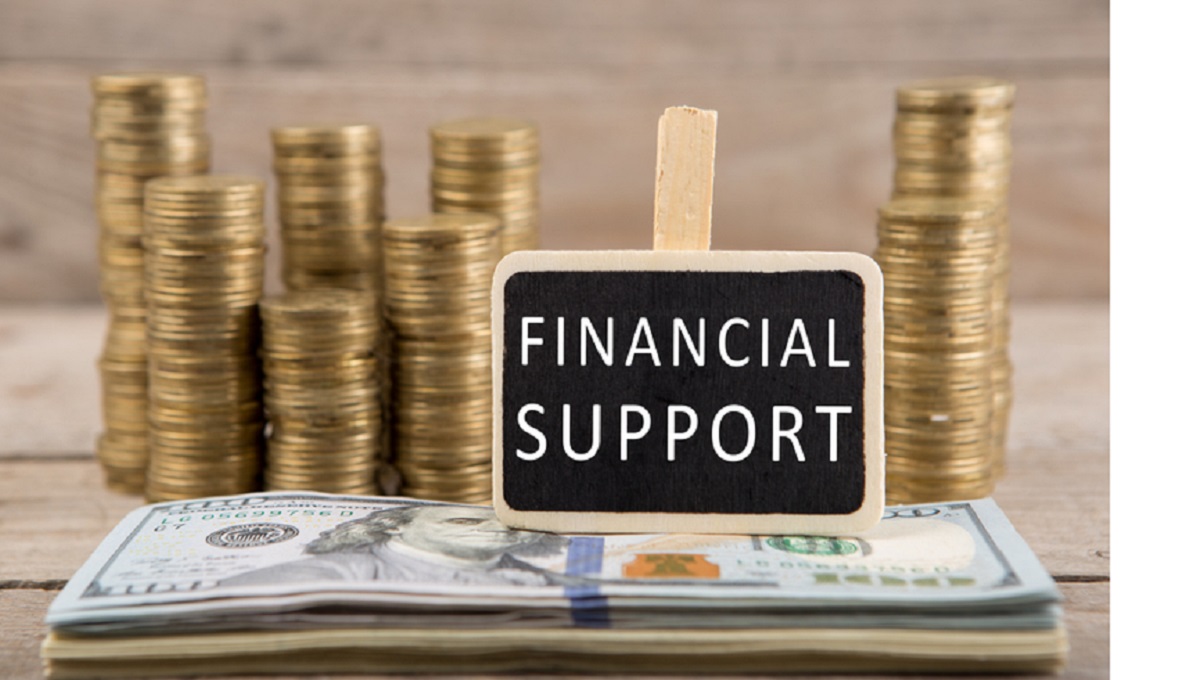 Stacks of coins and dollar bills, blackboard with text "FINANCIAL SUPPORT"